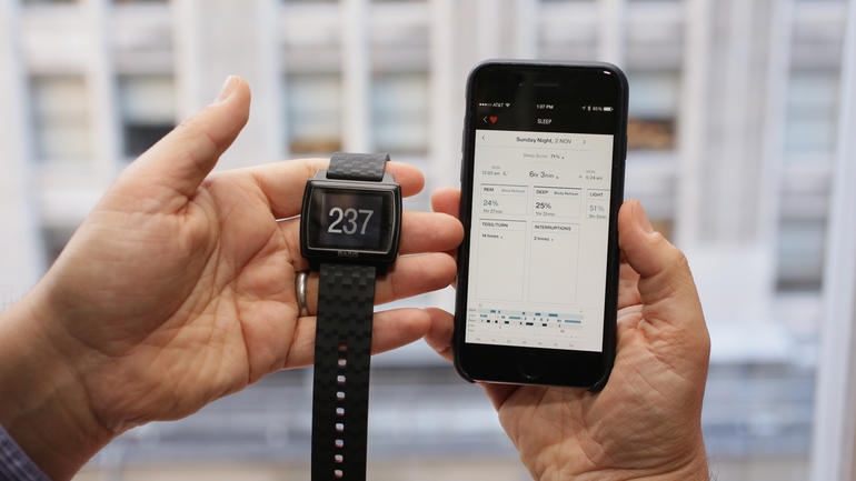 A Basis Peak watch next to a smartphone.