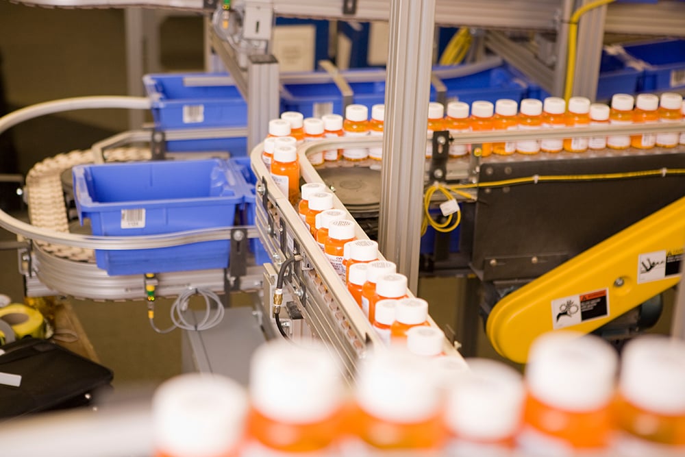 Pill bottles move down an assembly line in a factory.