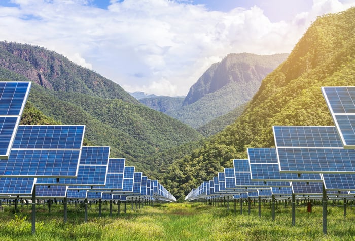 Solar farm with lush mountains in the background.