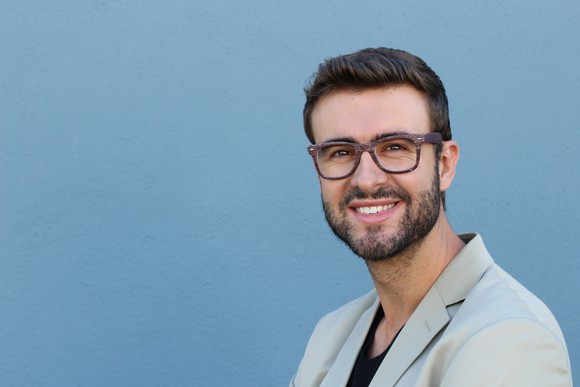 A smiling younger man with glasses and a close-trimmed beard.