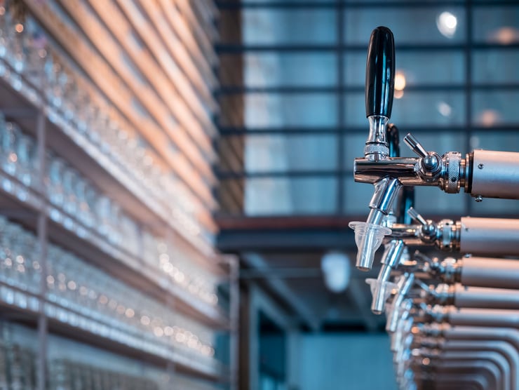 Line of chrome and silver beer taps in an industrial style bar.