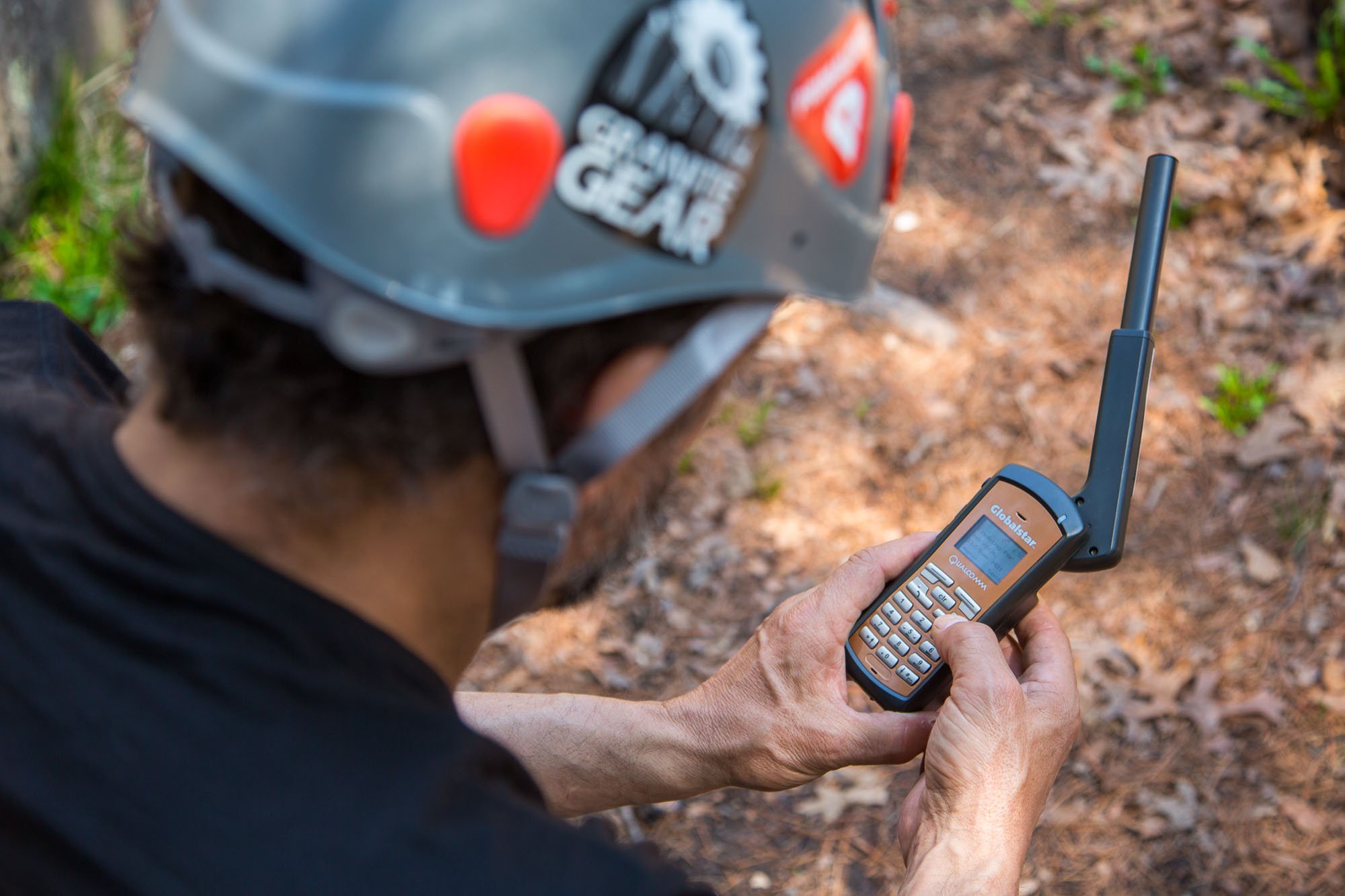 A man hiking in the wilderness using a Globalstar satellite phone.