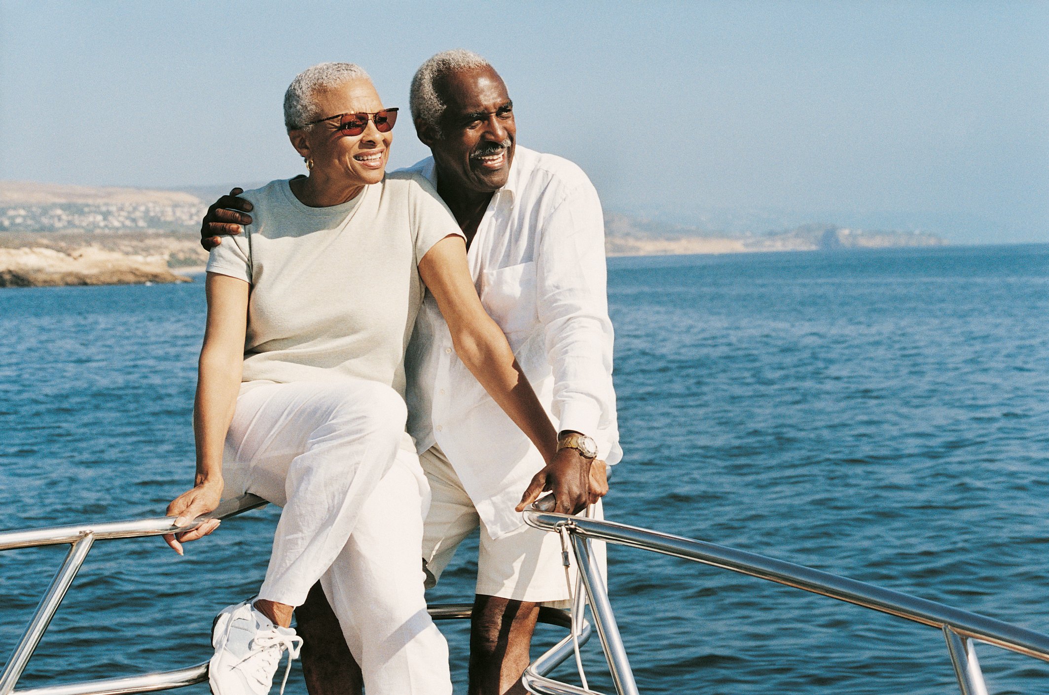 Senior couple standing on boat looking toward the sun and smiling