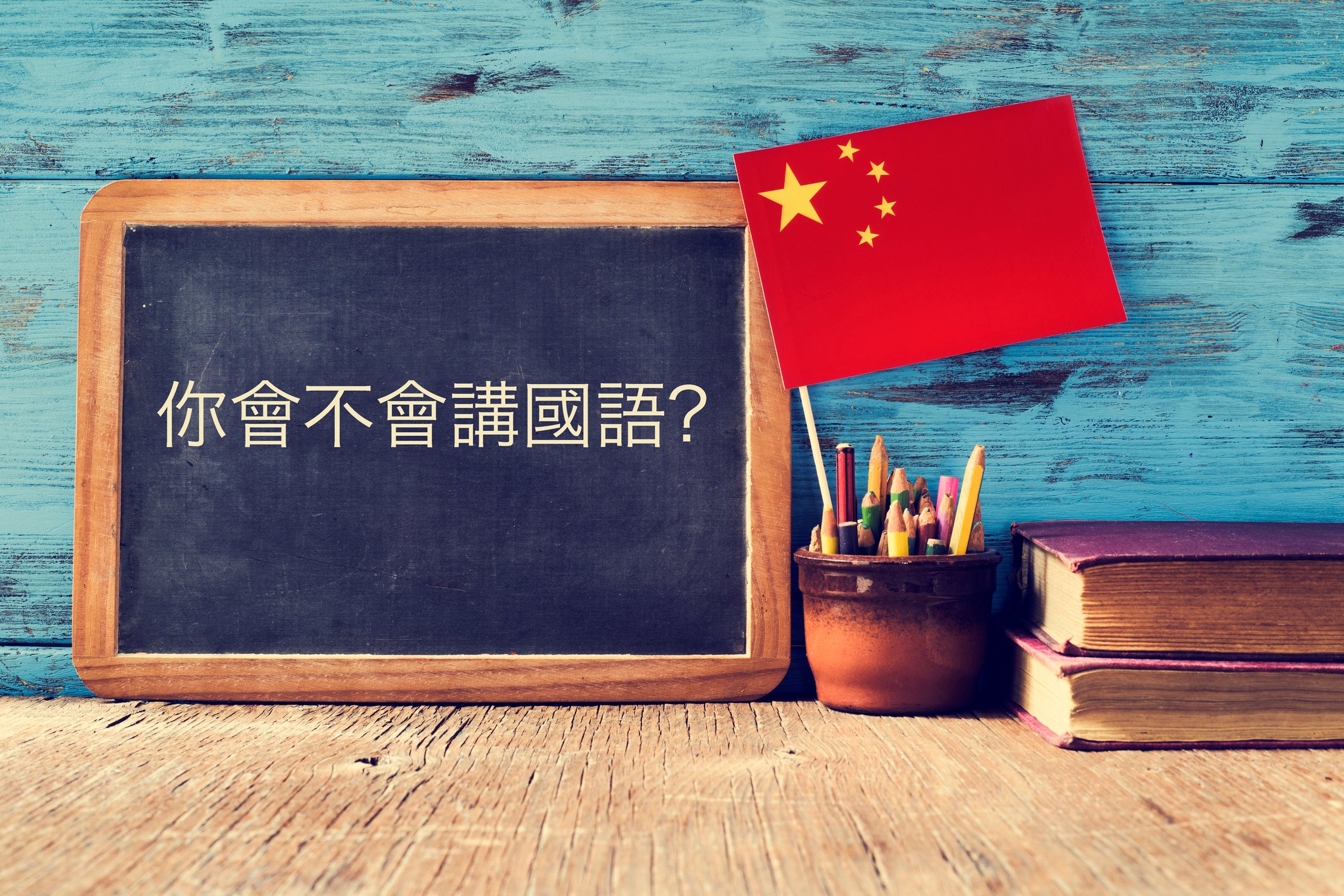 A chalkboard with Chinese characters written on it next to a Chinese flag.