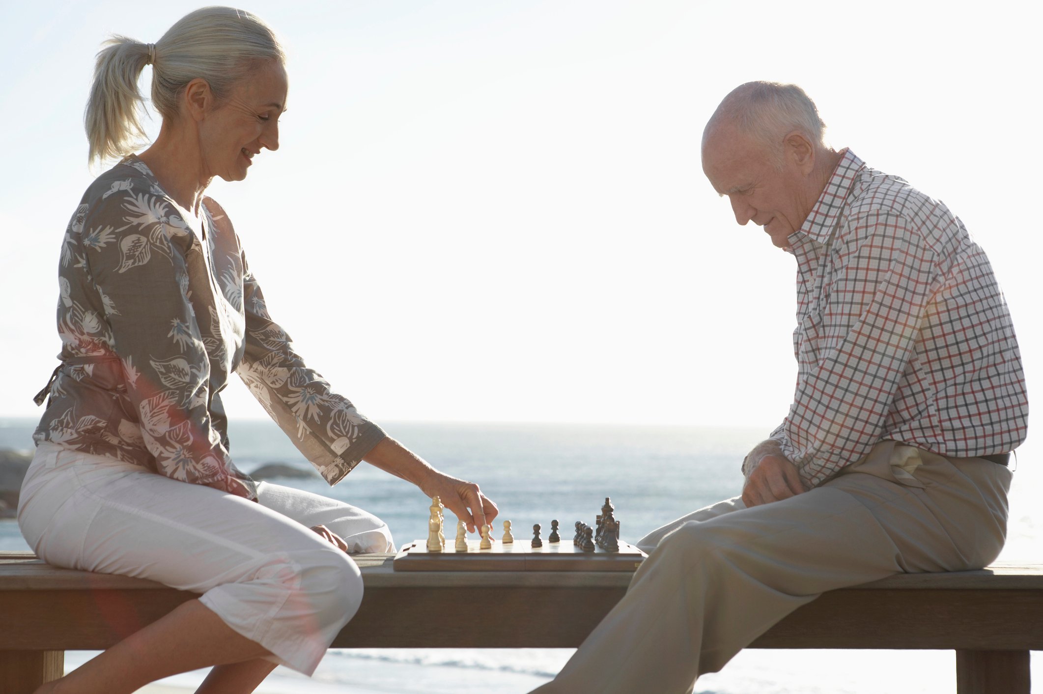 Senior couple playing chess on the beach