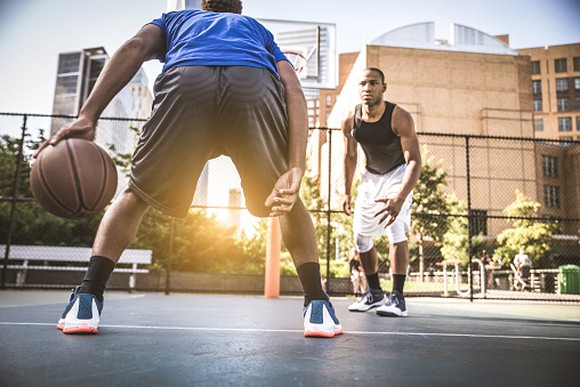 Two young men playing basketball outside