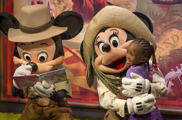 Mickey and Minnie Mouse greet a young child.