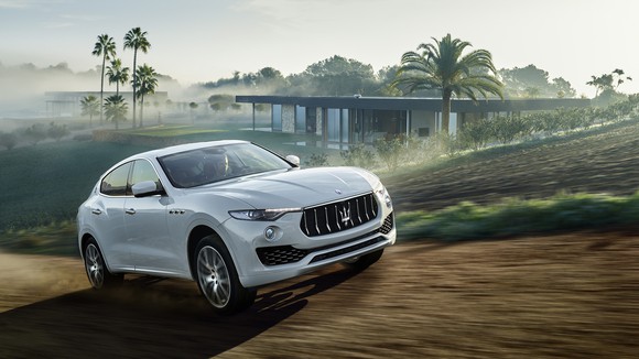 A white Maserati Levante SUV in a tropical setting.