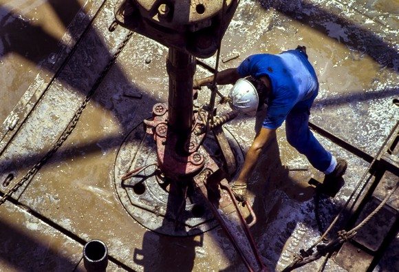An oil rig worker fitting a pipe