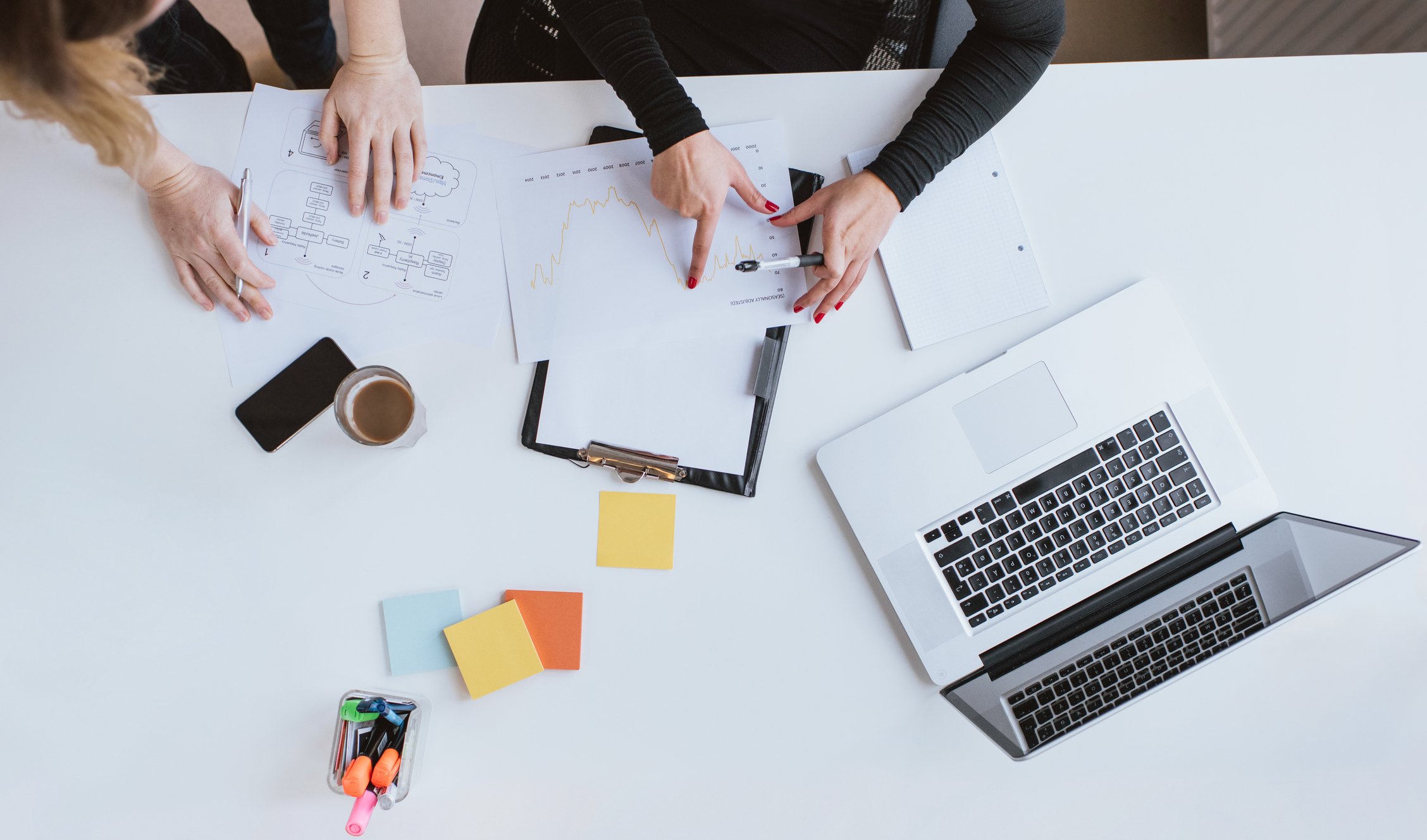 An overhead view of two people at a workstation, collaborating on a project.