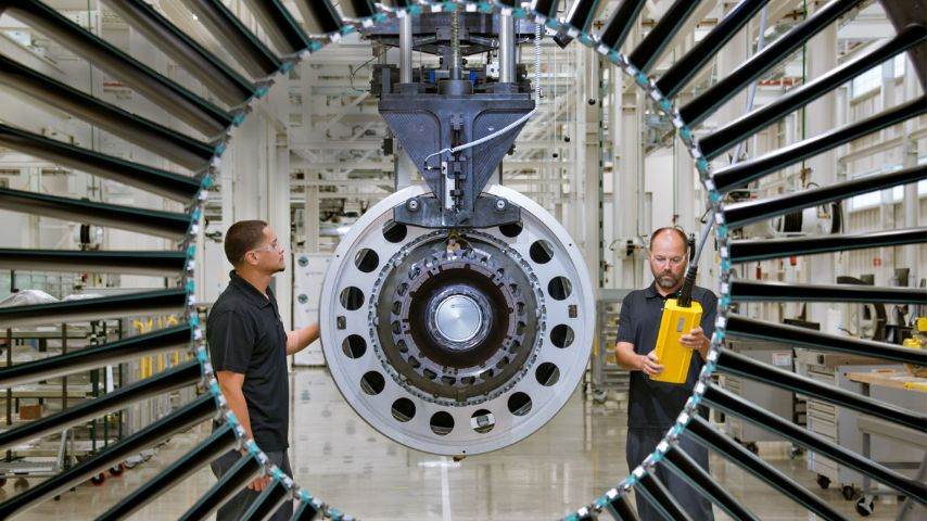 Two workers stand around a geared turbofan