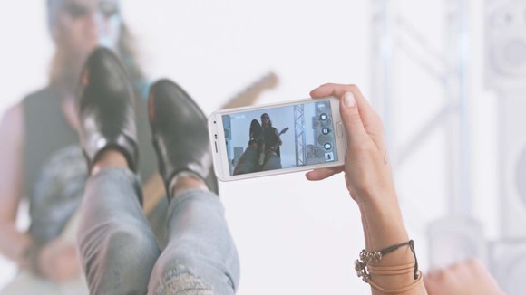 Someone filming someone play guitar on a smartphone.