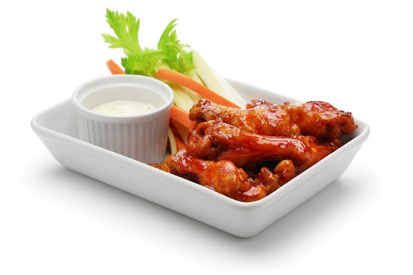 A plate of Buffalo chicken wings, celery, and ranch dressing.