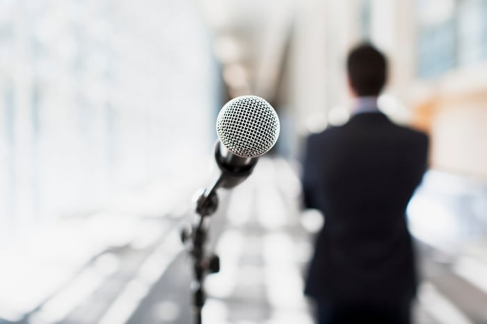 A microphone stand with an image of a business man in the background.