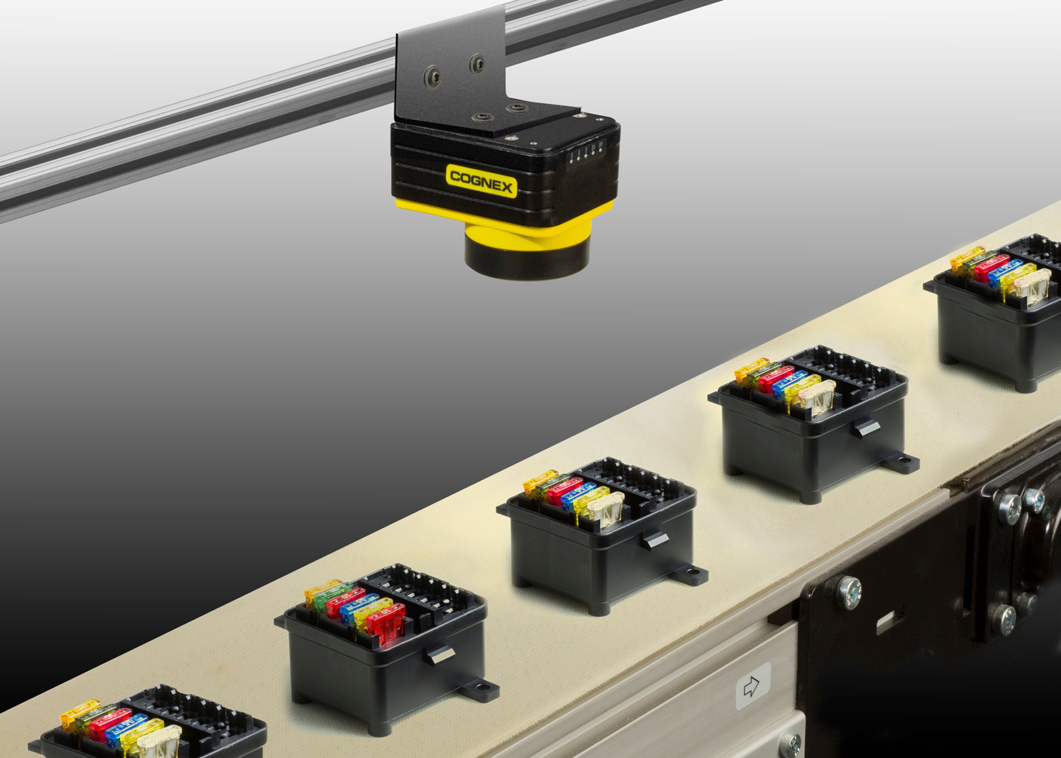 A Cognex machine vision system mounted above conveyor belt with various objects.
