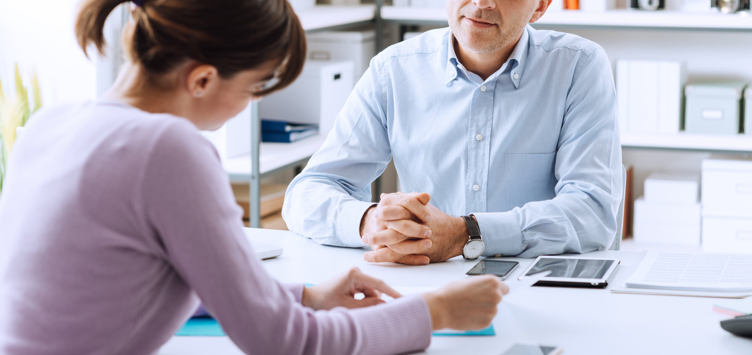 A woman points to a piece of paper as she talks with a man across the table.