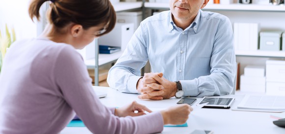 A woman points to a piece of paper as she talks with a man across the table.