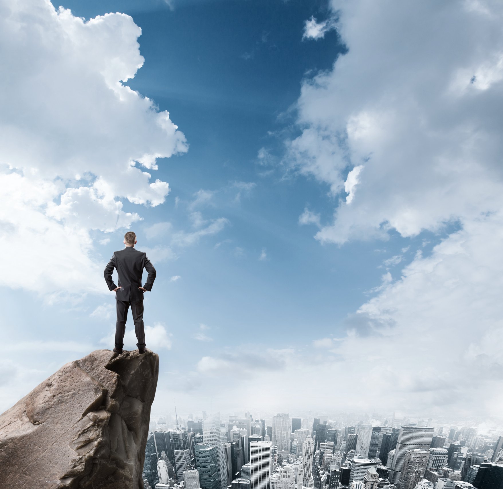A businessman looking out at a city from a perch above the clouds