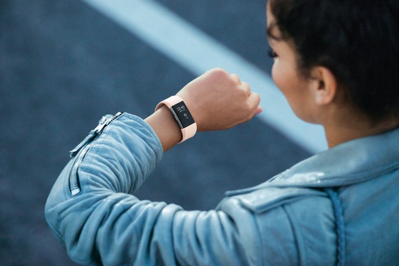 A woman looking at a Fitbit Charge 2 on her wrist.