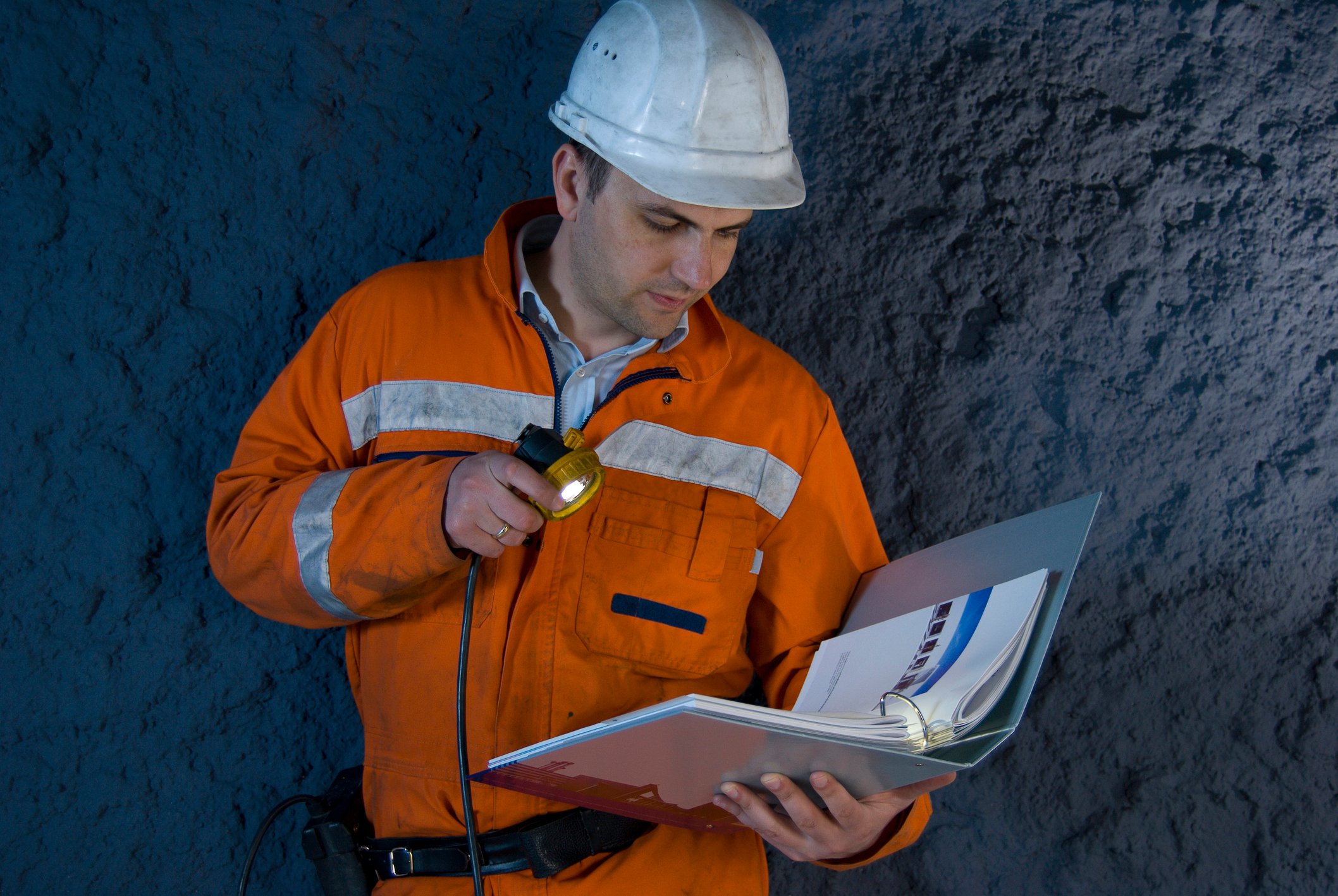 An engineer looking at a binder with a flashlight