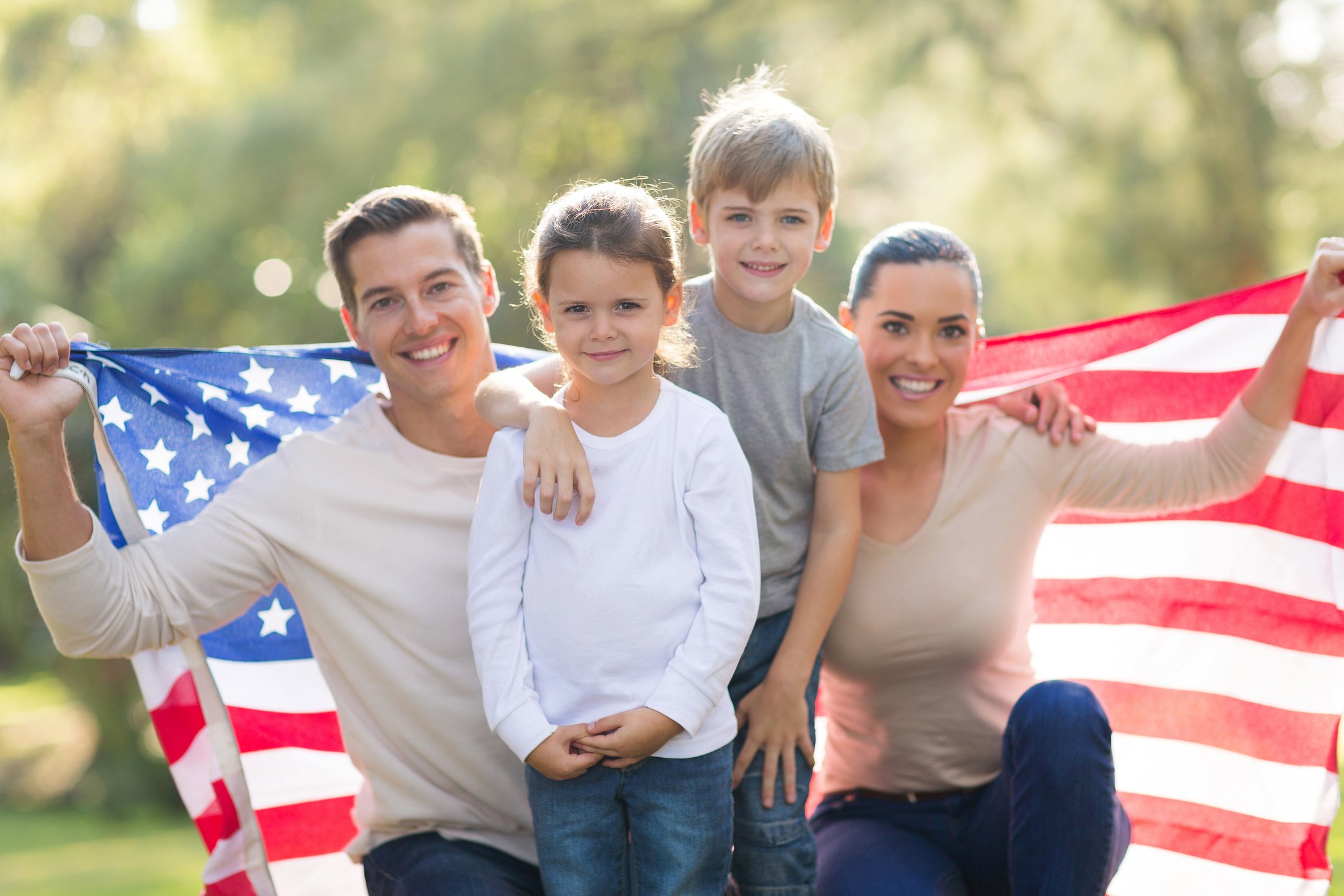 Smiling family holding up an American flag
