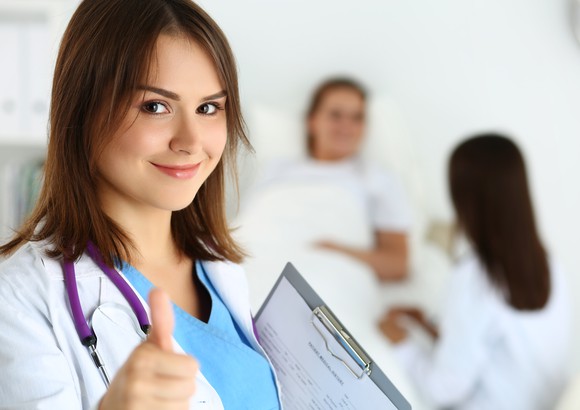 A doctor gives a thumb's up in a hospital room.