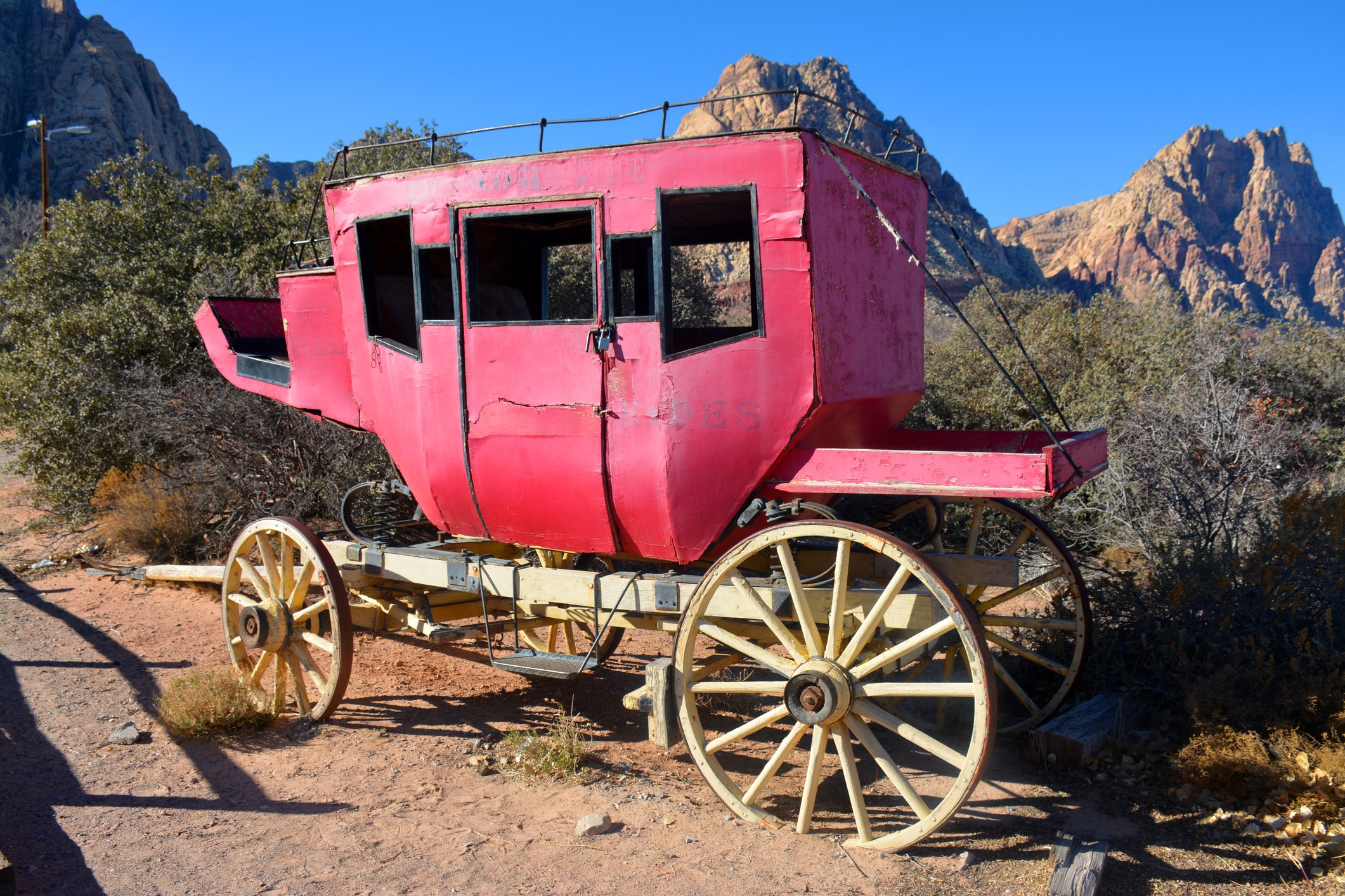 An old, red stagecoach parked in the desert.