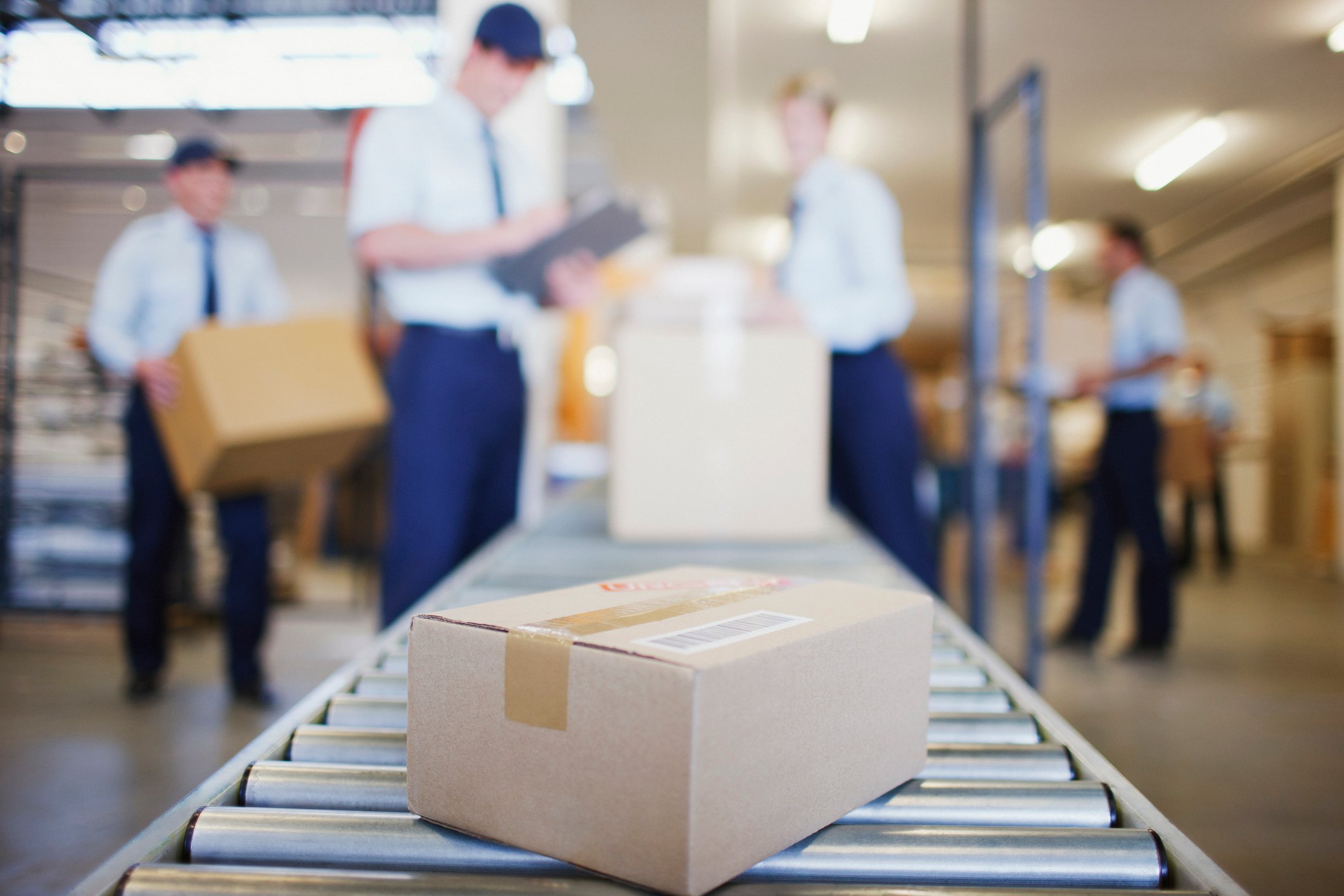 People placing packages on a conveyor belt.