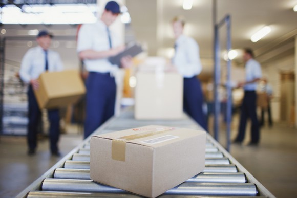 People placing packages on a conveyor belt.