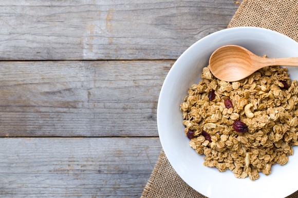Bowl of cereal with a spoon on a wooden table. 