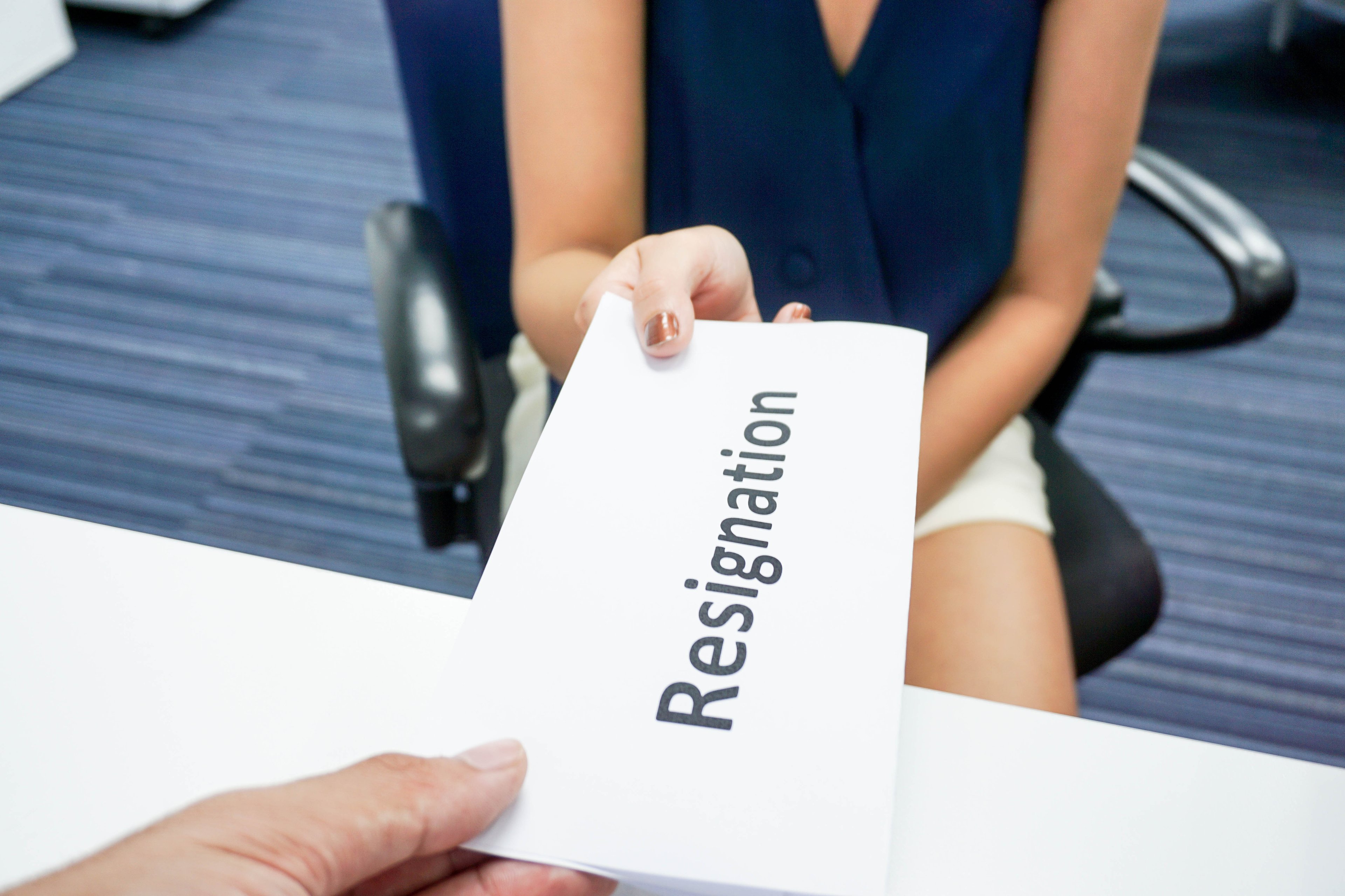 Businesswoman handing in paper that says "resignation"