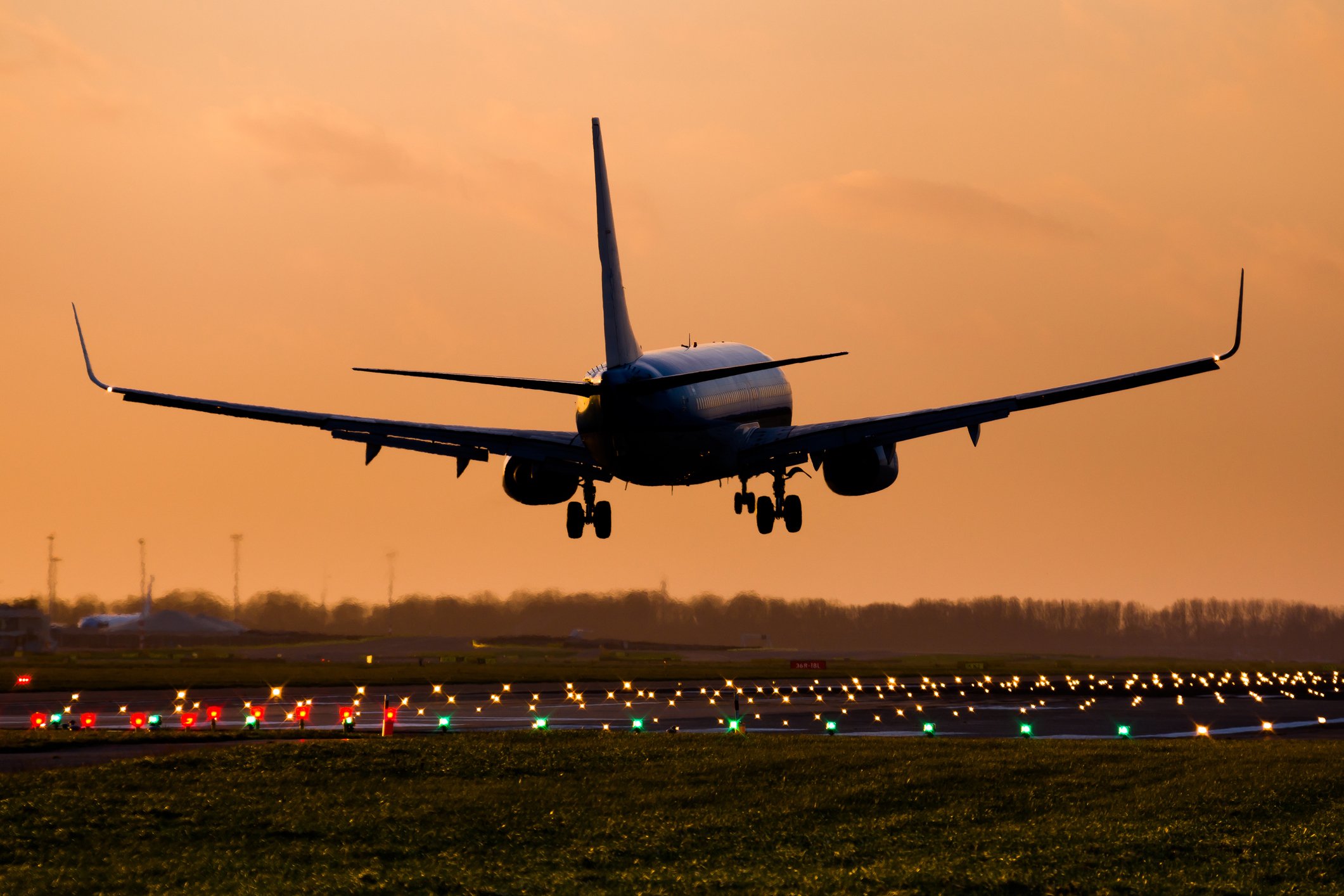 A commercial jet plan lands at sunset.