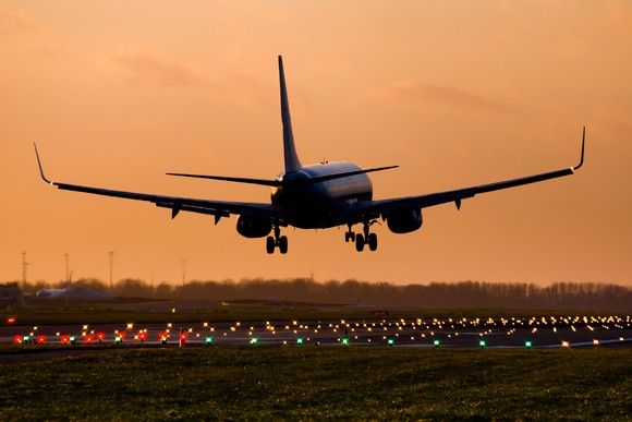 A commercial jet plan lands at sunset.