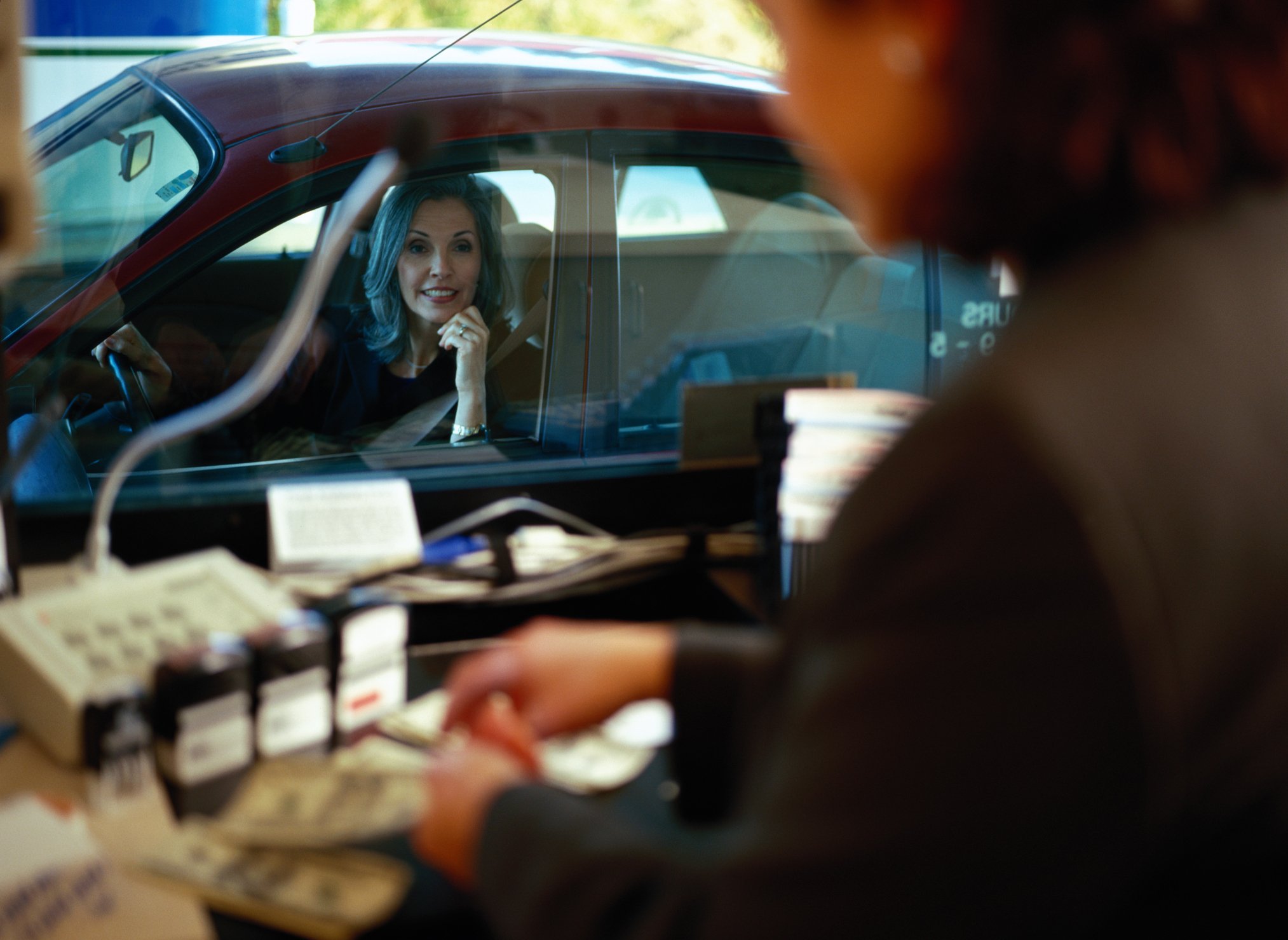 A woman in her car seen from a drive-through teller's booth