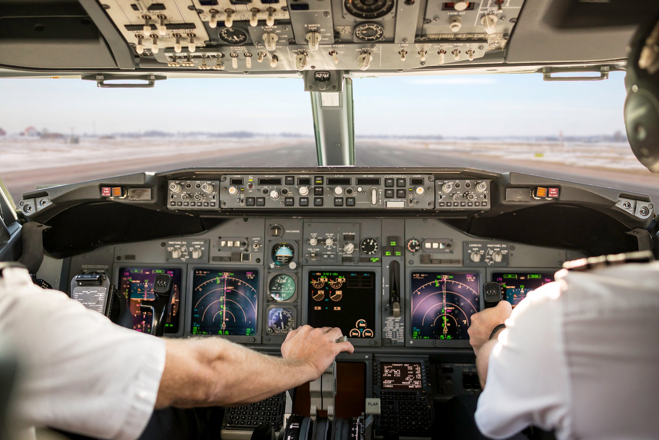 A pilot pulls back the throttle in a cockpit.