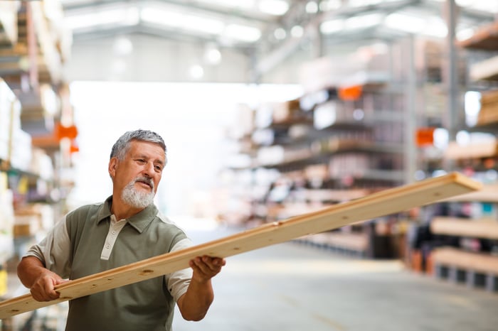 A customer inspects a piece of lumber. 