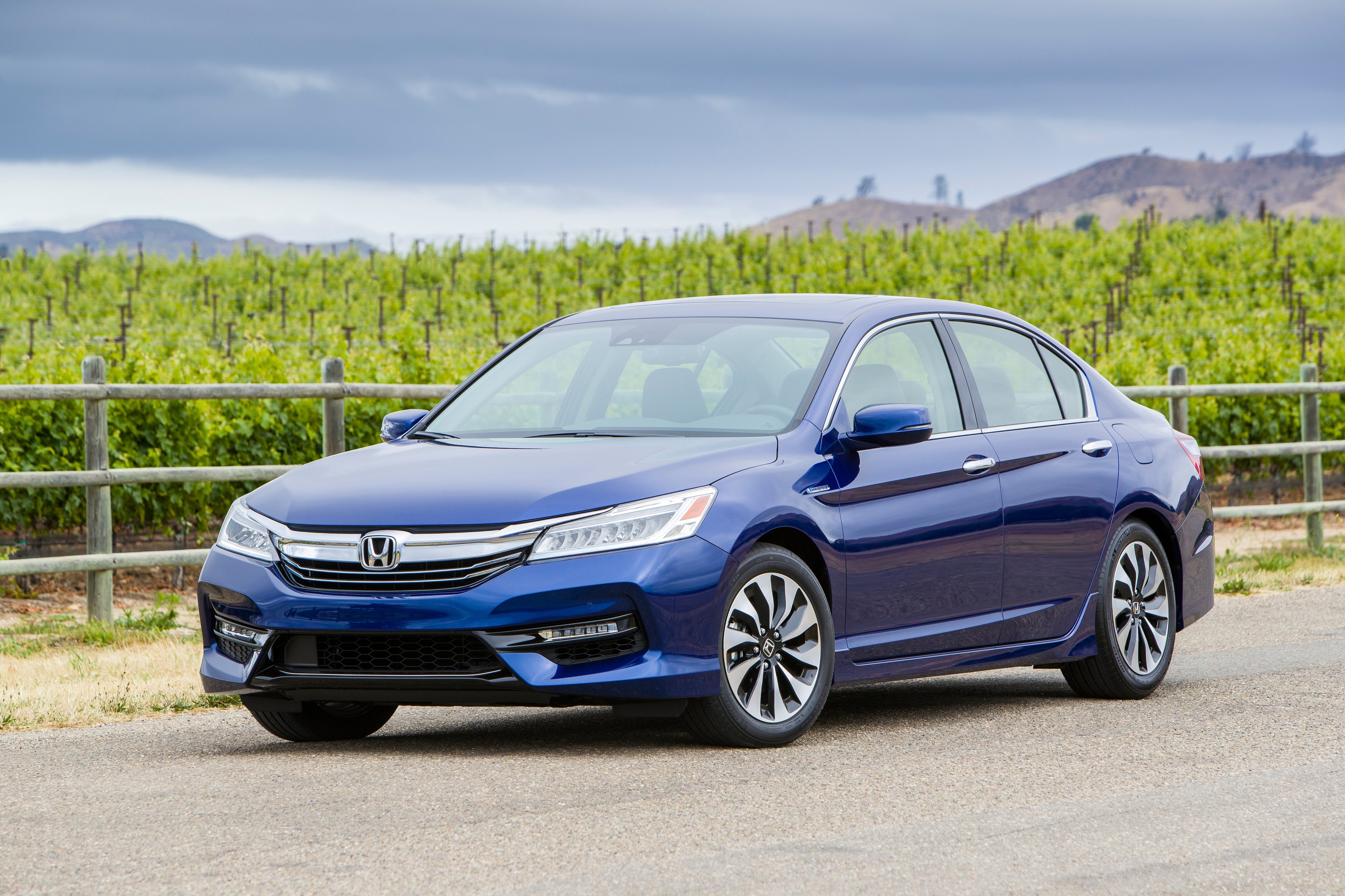 A blue 2017 Honda Accord Hybrid sedan parked on a country road. 