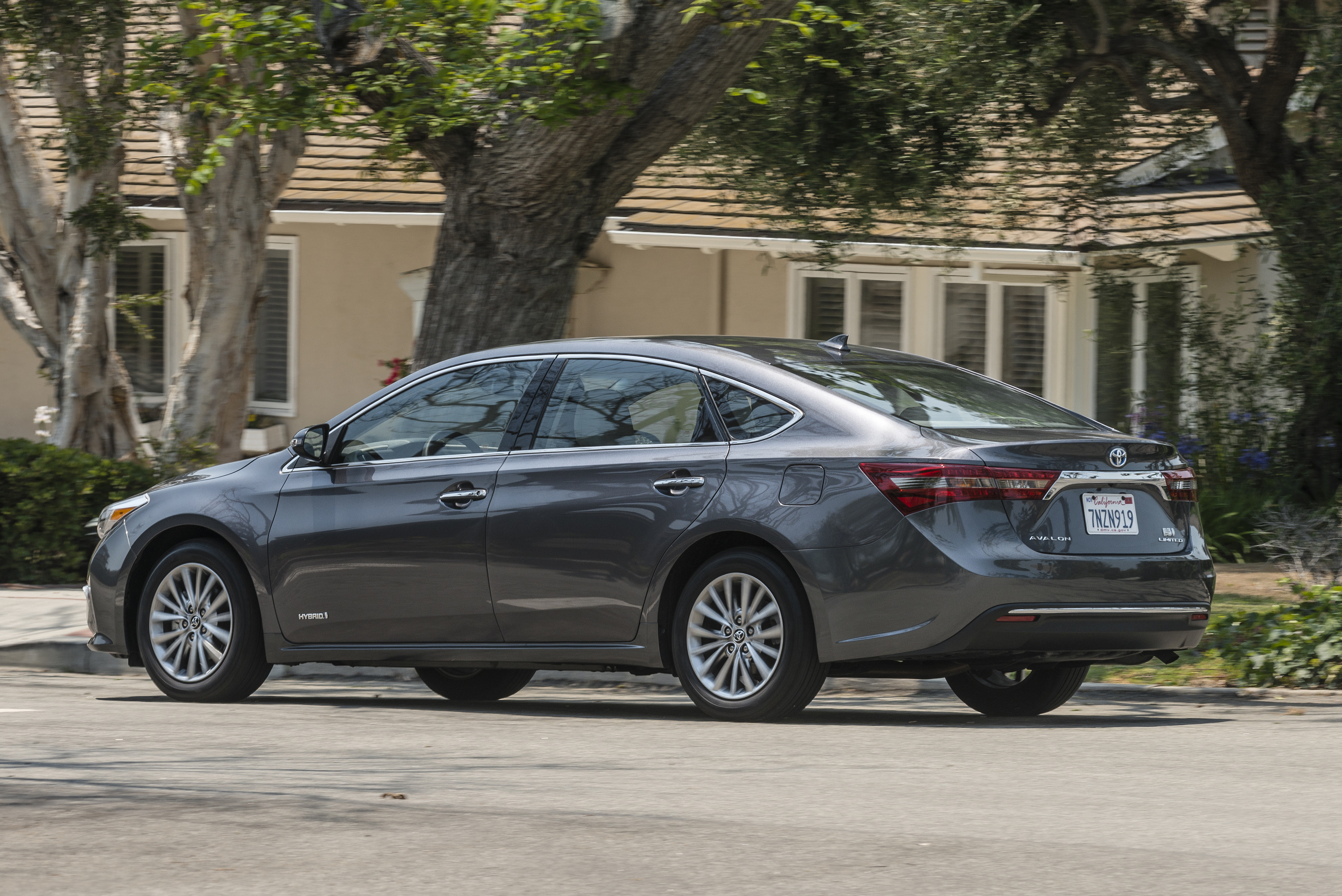 A dark gray 2017 Toyota Avalon Hybrid Sedan parked in front of a house. 