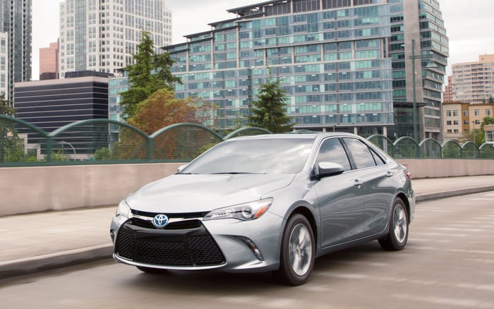 A silver 2017 Toyota Camry Hybrid on a road near office buildings. 