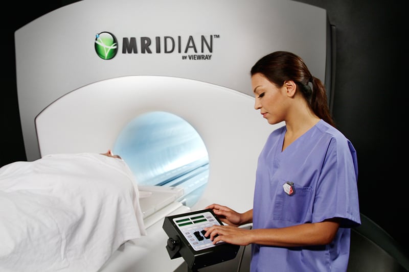 A nurse stands beside a MRIdian system.