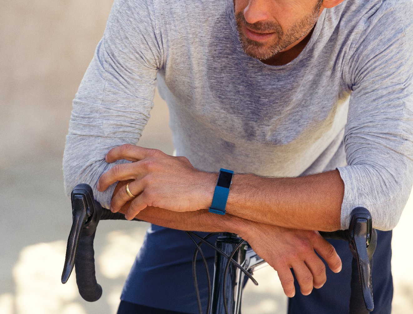 Sweaty guy resting on his bike wearing a Fitbit Charge 2.