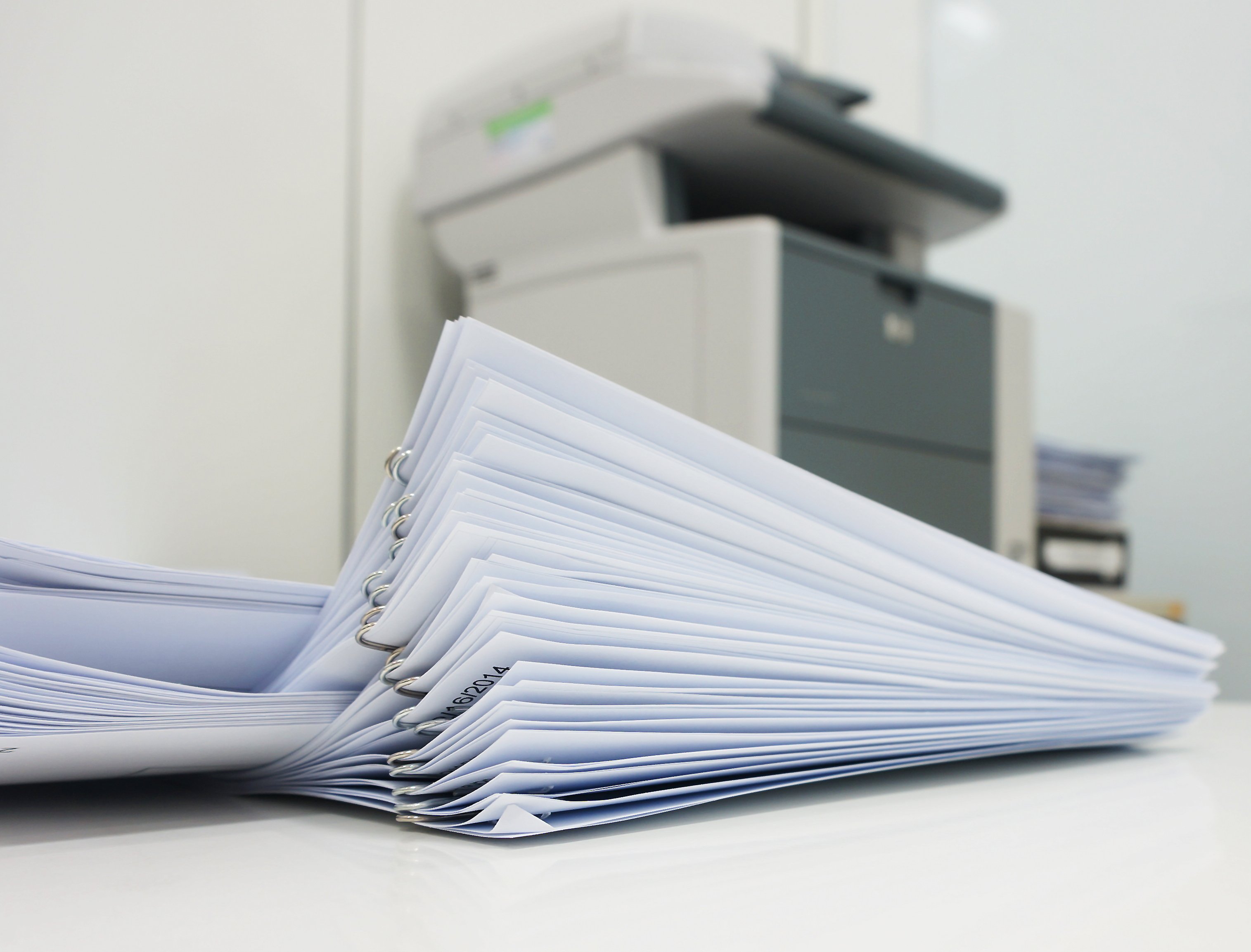 A stack of papers in front of a copy machine.