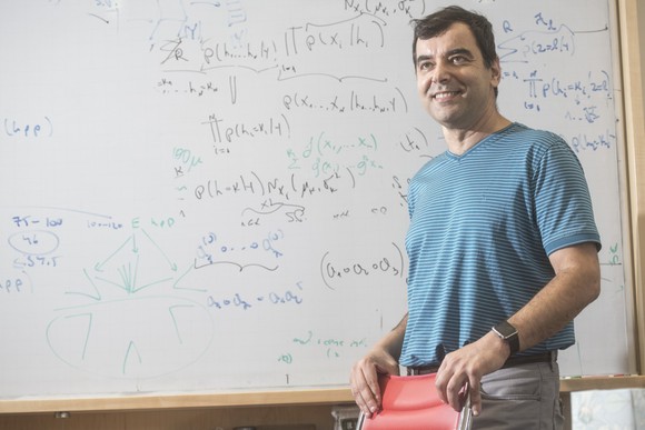 Shashua is standing before a whiteboard covered with calculations. 