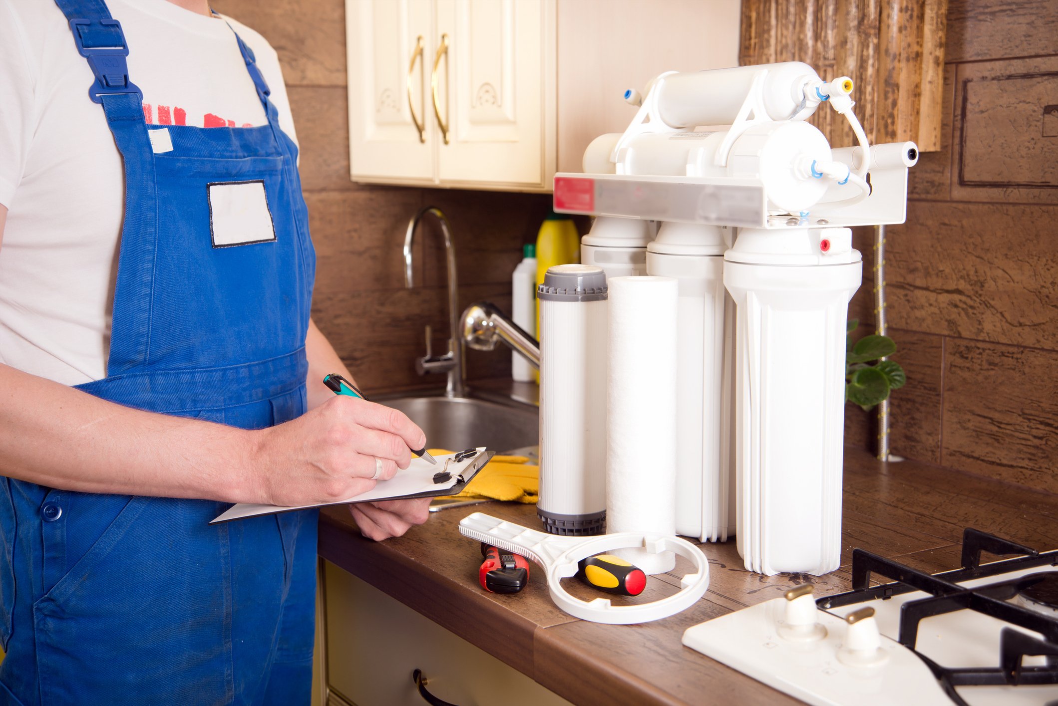 A plumber installing a water purification system in a kitchen