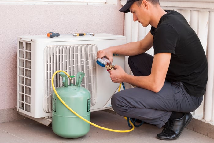 Man adding coolant to an air conditioner.