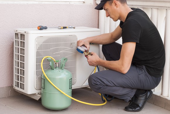 Man adding coolant to an air conditioner.