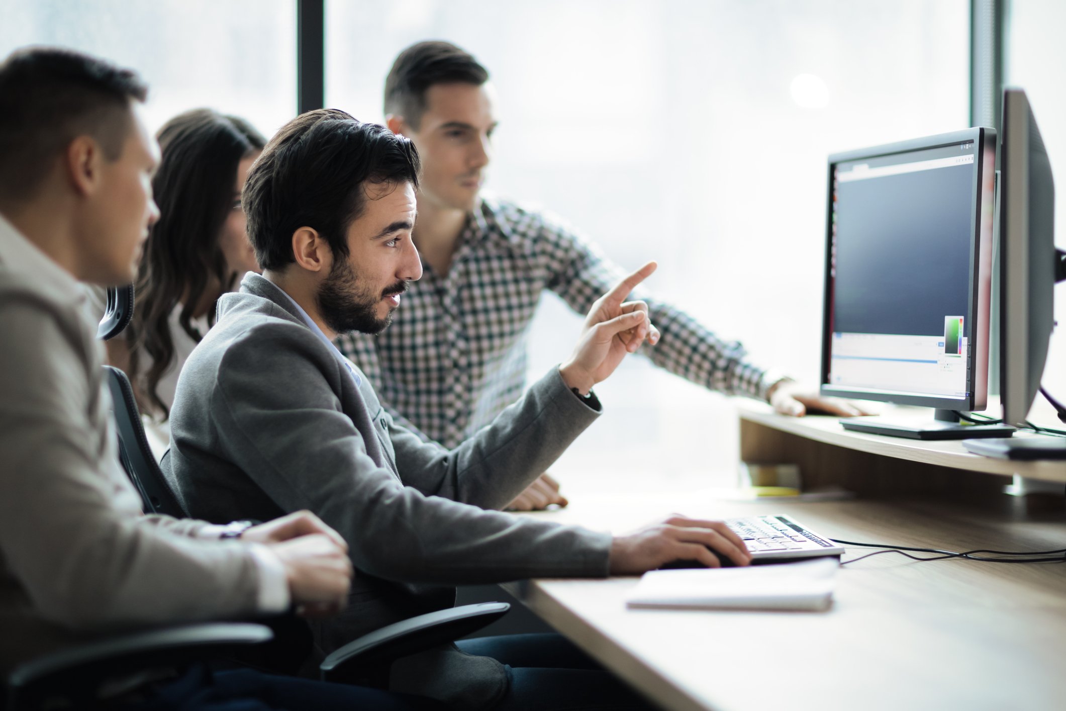 Software engineers hovering over a computer while working on a project together