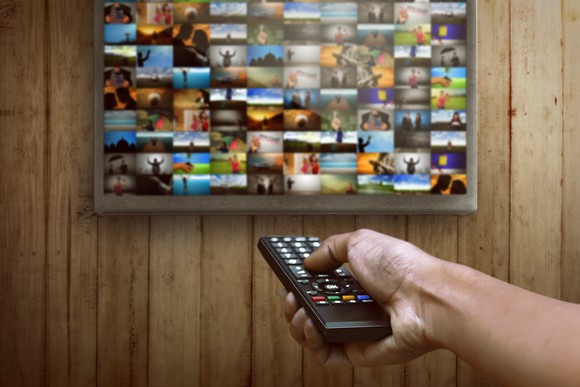 Person choosing channel on the television with remote.