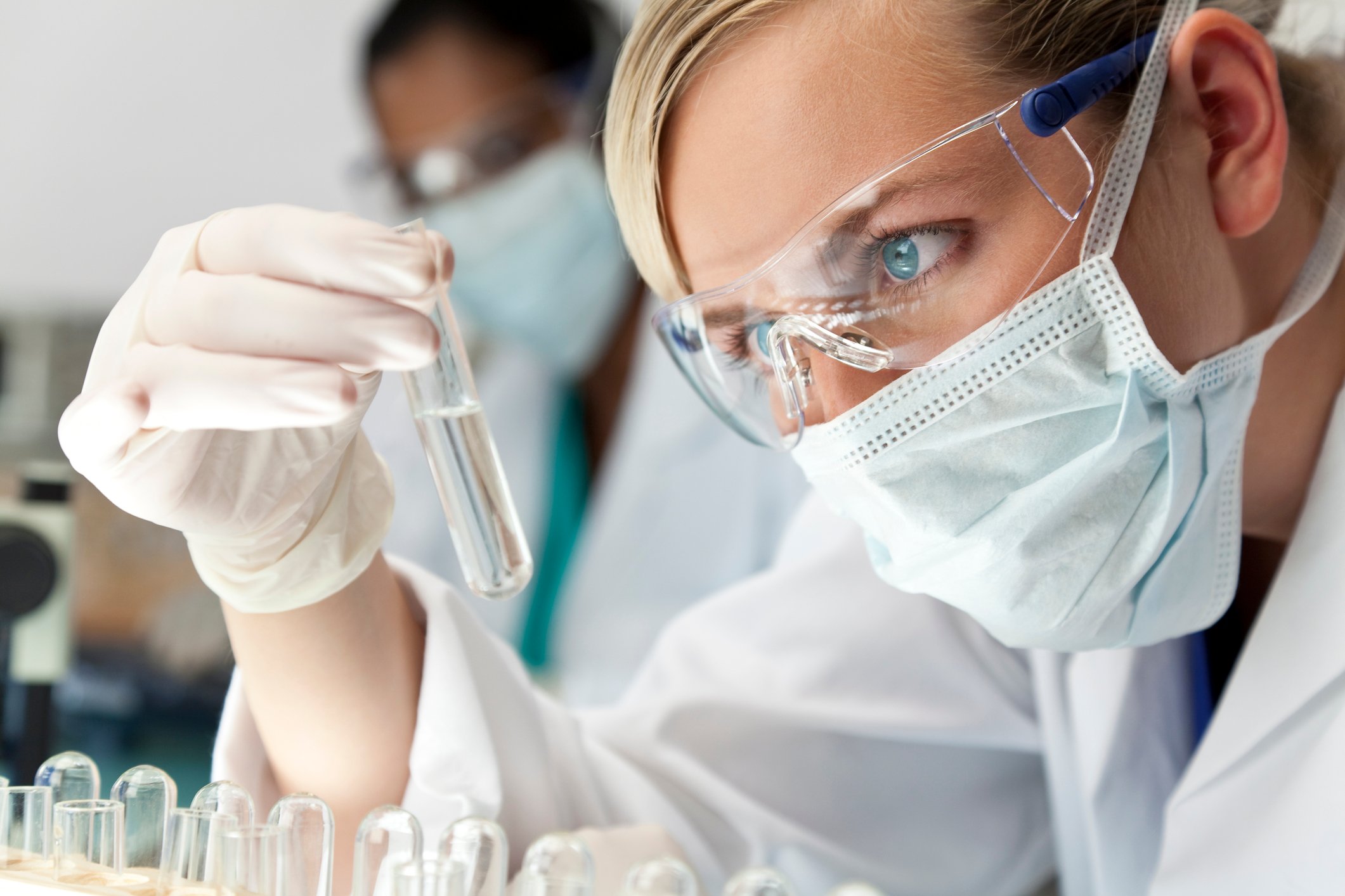 A lab researcher examining a test tube in her hand.