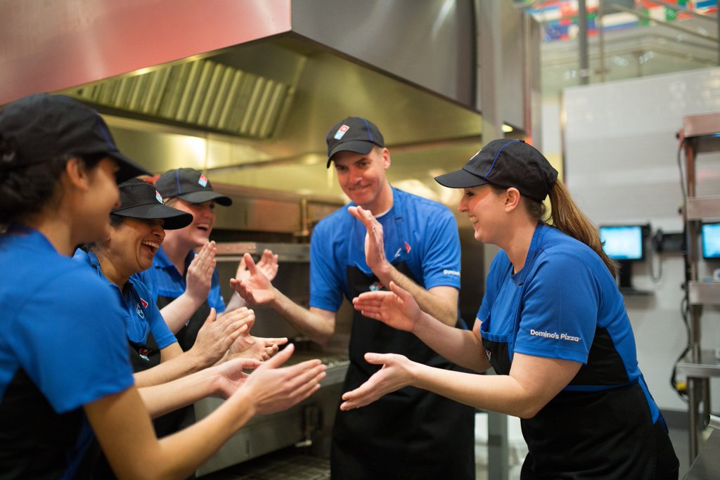 Domino's employees clapping during a meeting.